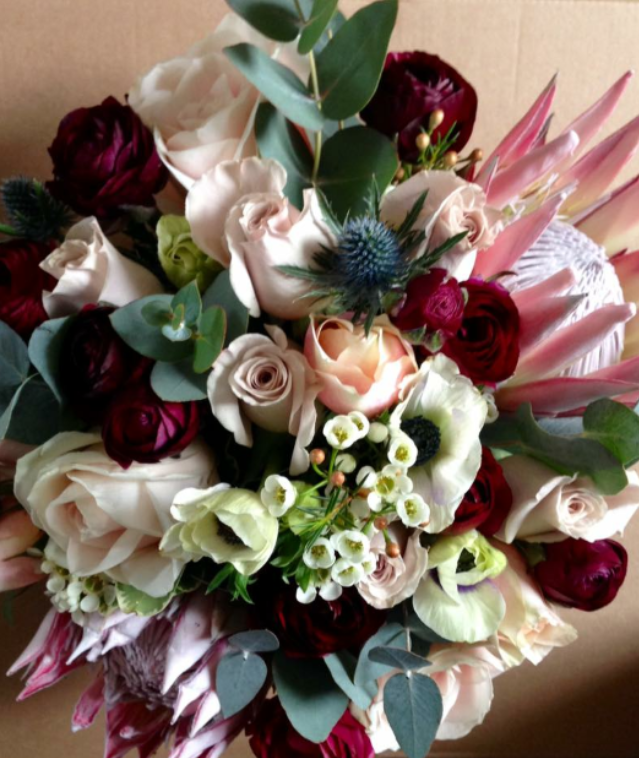 burgundy pinks & blue thistle wild looking bridal bouquet in the countryside