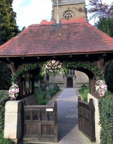 sprays of pink flowers soft ruscus large spray over arch Church gate arch entrance