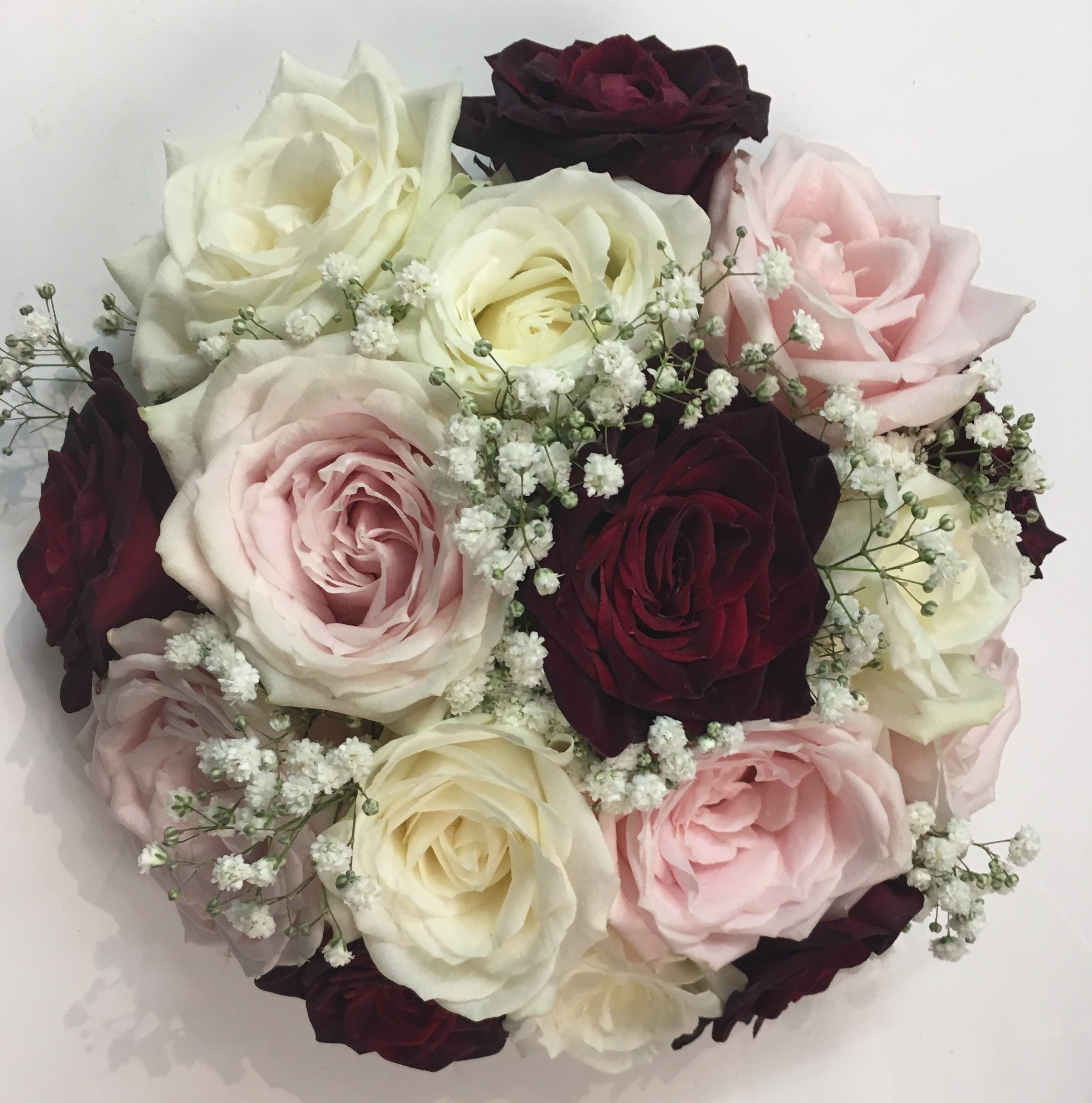 pastel and deep burgundy  flowers in bouquet white roses and pale pink hand tied bouquet