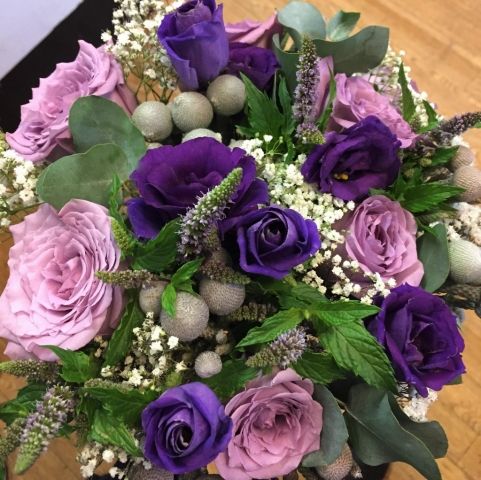 bridal flowers in a hand tied bouquet loose style of mint veronica and foliage lilac roses with ivory roses and purple lisianthus  hand tied wedding bouquet florist in studley flair with flowers