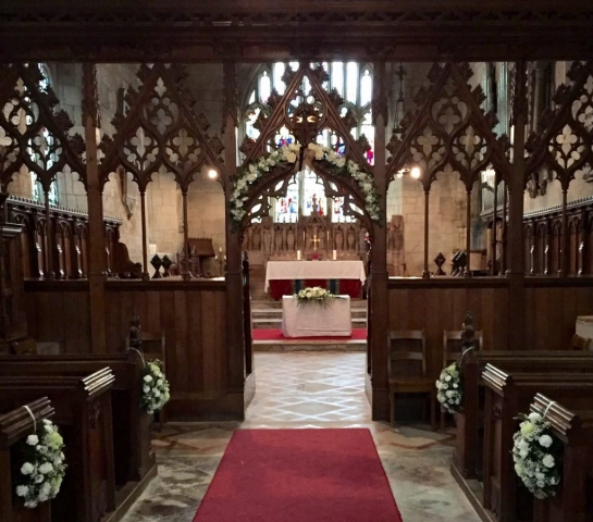 church dressing arch flowers alter arrangements pew ends white flowers Wroxall Abbey aisle arch with alter arrangement