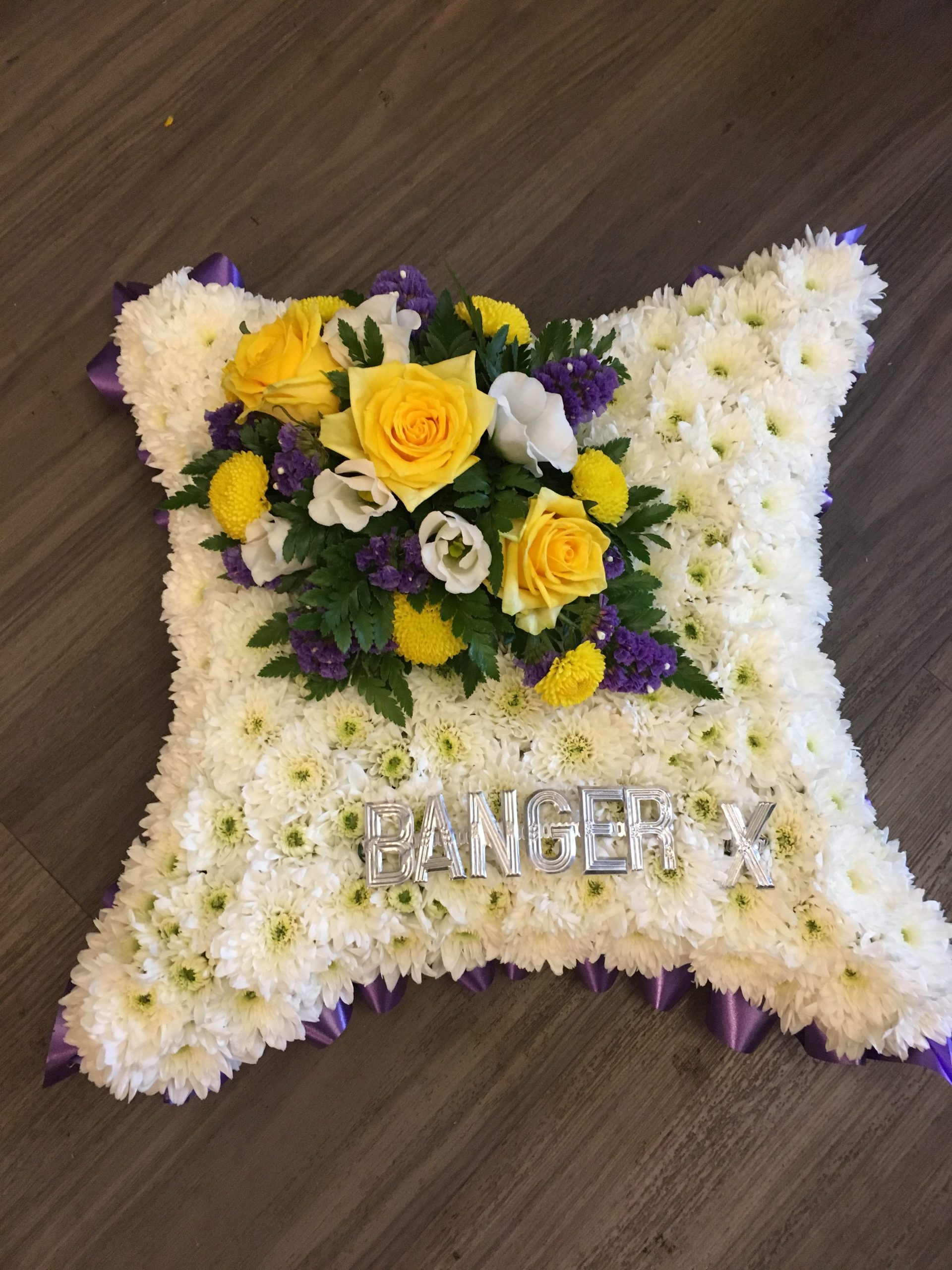 Cushion funeral tribute in yellow & purples
